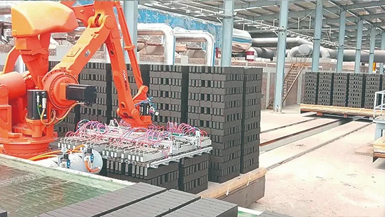 Orange palletizing robot stacking blocks in a factory